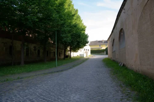 Dorfstraße: links langes Torhaus mit Durchgang zum Gutshaus, rechts Scheunen und Garagen